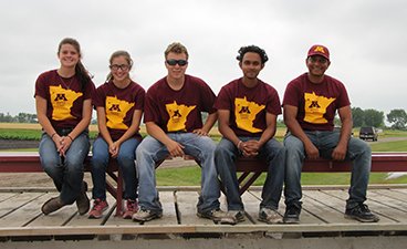 Five students sit on a bench in matching NWROC shirts